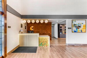 Zona de recepción de hotel con un mostrador de madera, un tapete negro y una decoración en forma de luna creciente en la pared.