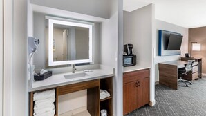 A modern bathroom with a large mirror, white sink, and wooden vanity. There is a microwave and a small desk with a chair. - Comfort Inn & Suites Ogallala (Ogallala)