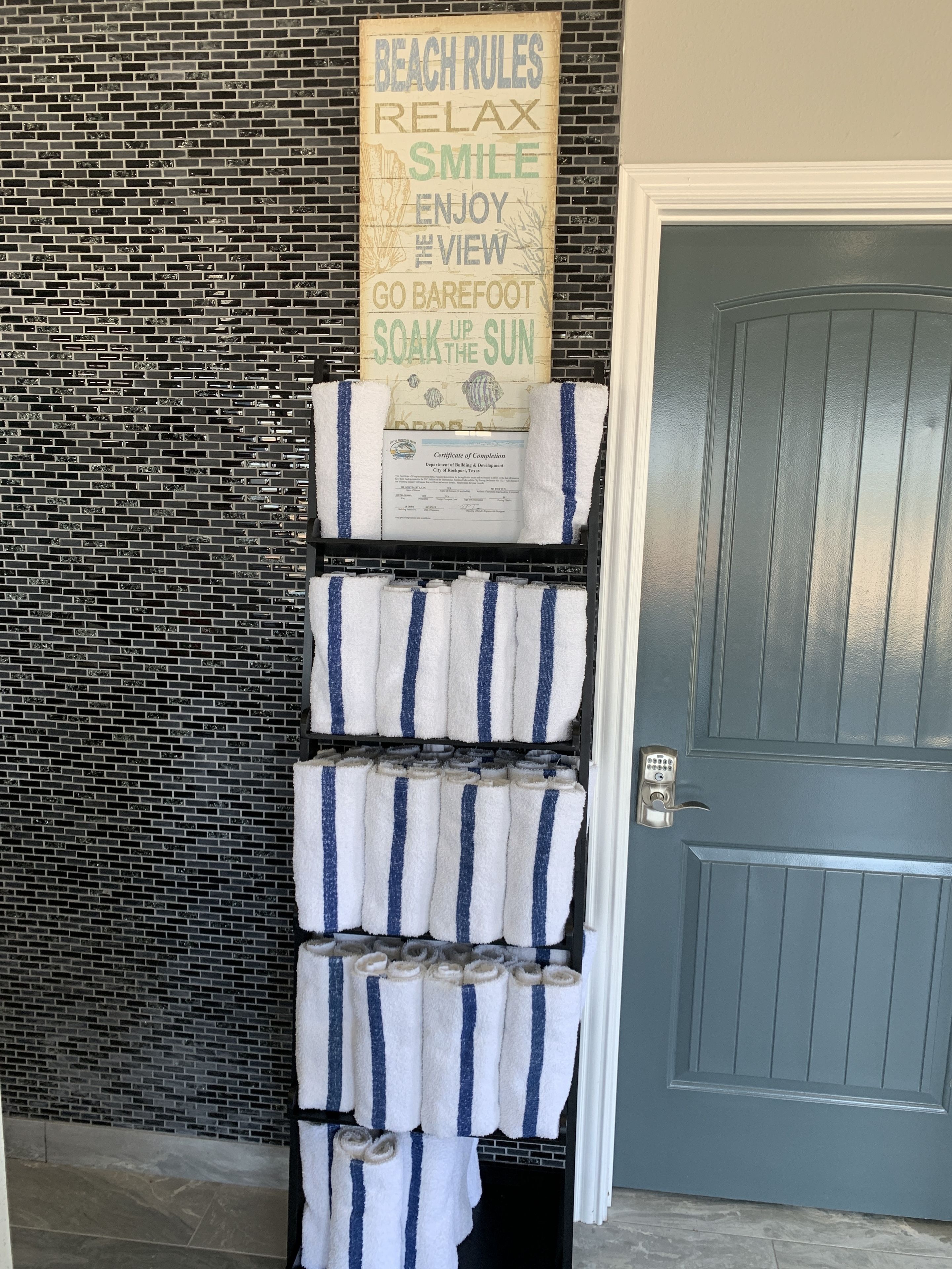 A towel rack with striped towels in front of a brick wall and a door.