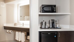 A compact kitchenette with a microwave, coffee maker, and a small refrigerator.