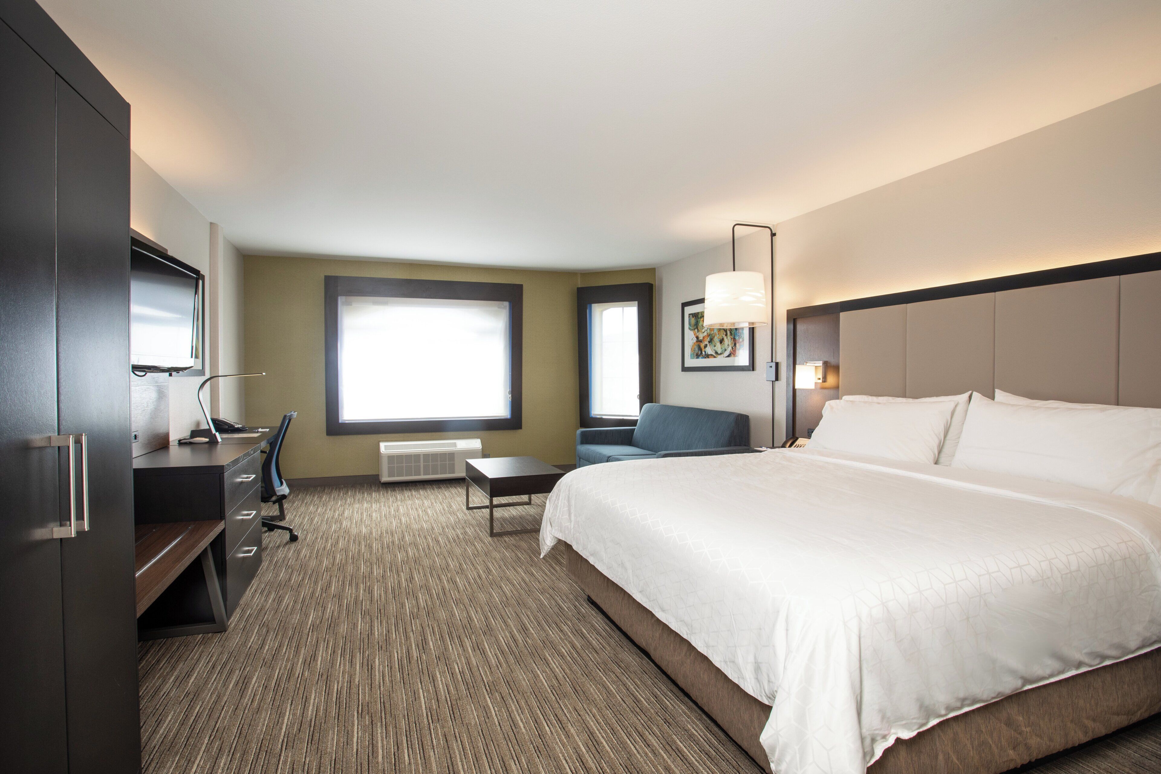 Een hotelkamer met een bed, bureau, stoel en een groot raam.
