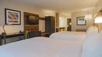 A hotel room with two beds, a desk, a chair, a TV, and artwork on the walls.