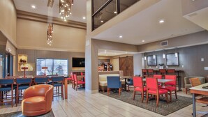 A modern hotel lobby with a dining area, a sofa, and a TV.