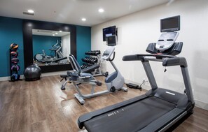 A gym with treadmills, elliptical machines, and free weights.