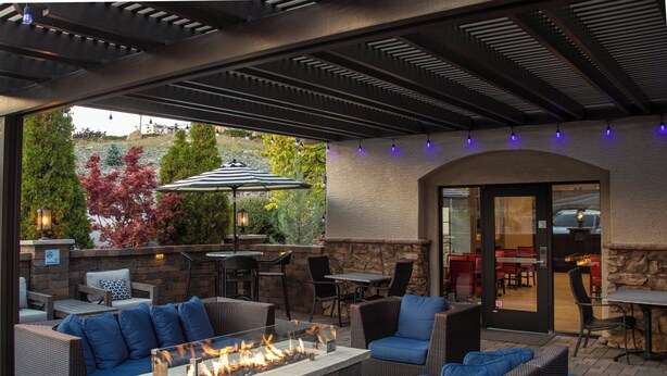 An outdoor patio with wicker furniture, a fire feature, and stone walls.