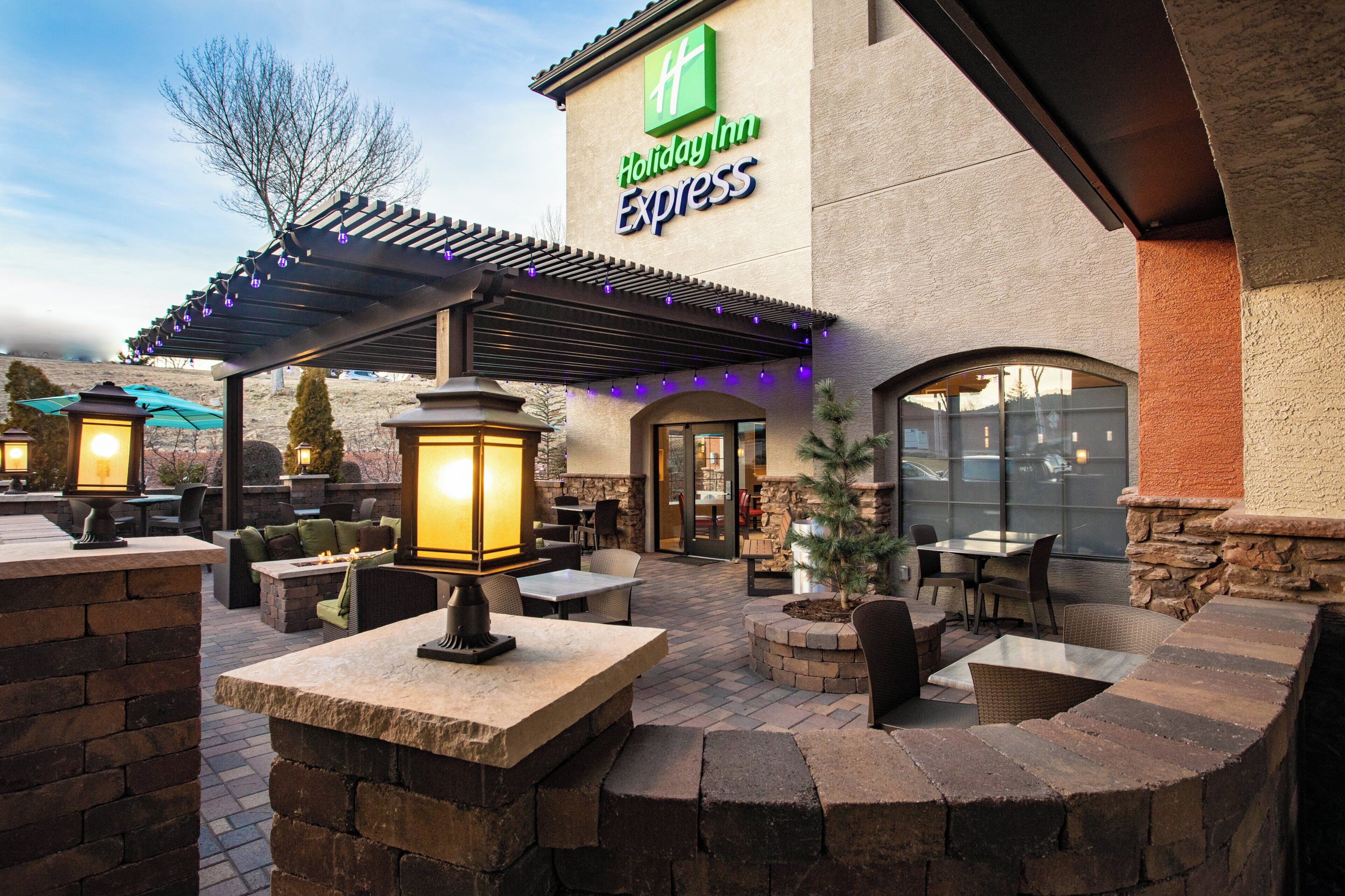 Un área de estar al aire libre con mesas y sillas, una chimenea y un letrero de Holiday Inn Express.
