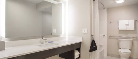 A modern bathroom with a large mirror, a sink, a toilet, and a shower area.