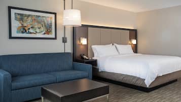 Une chambre d’hôtel avec un lit, un canapé bleu, une table basse et un tableau au mur.