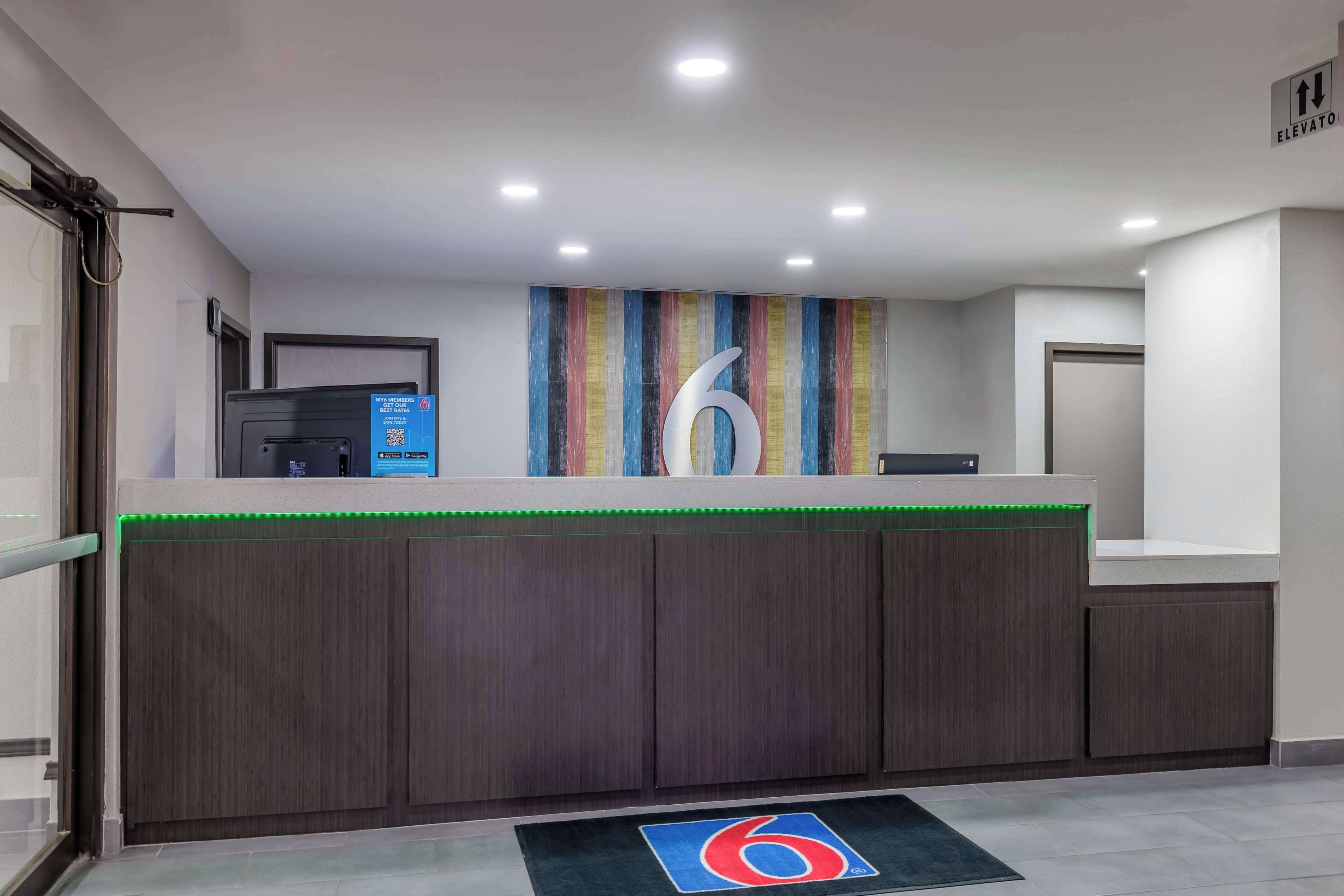 A reception desk with a large number '6' sign, a QR code, and a wheelchair accessibility symbol.