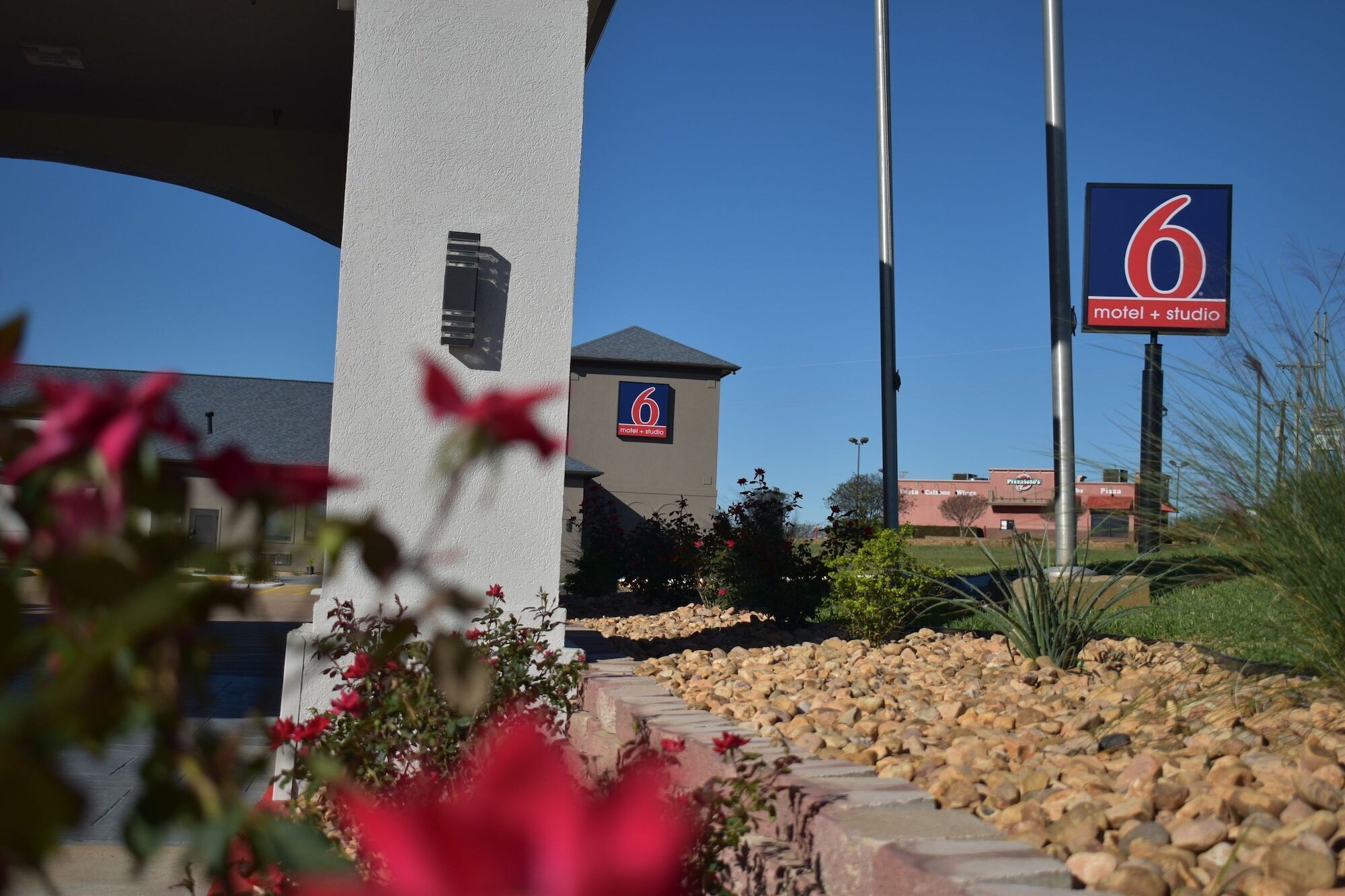 A motel with a prominent '6' sign, a small tower-like structure, and a clear sky.