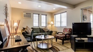 A living room with a sofa, armchair, TV, and a coffee table.