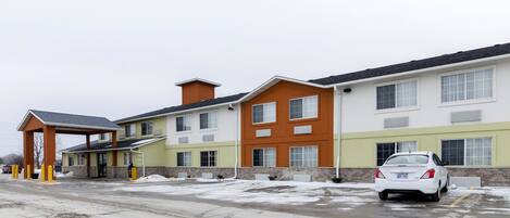 A multi-story hotel with a parking lot and a covered entrance.