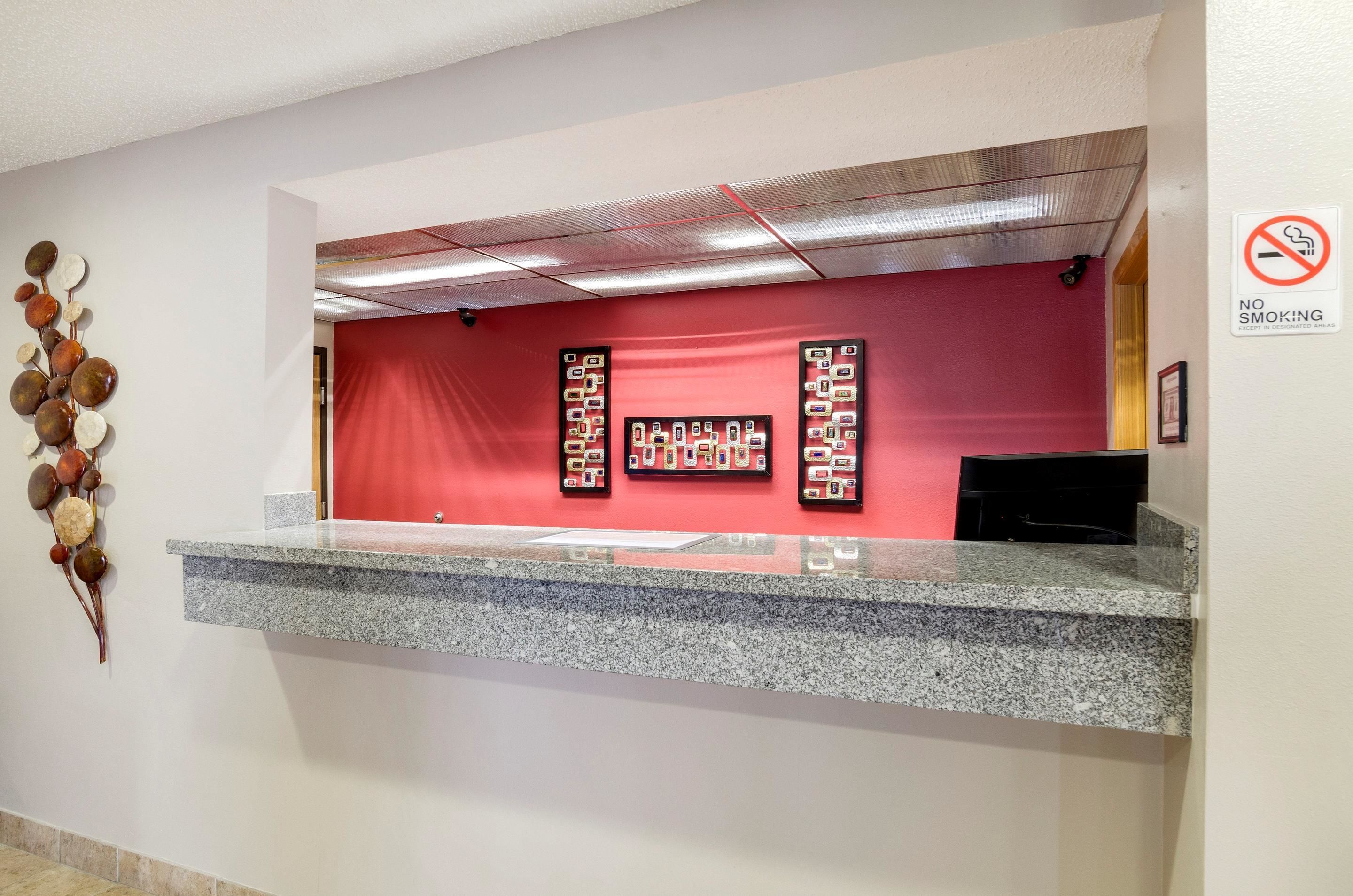 A reception desk with a red backdrop and a 'No Smoking' sign.