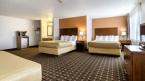 A hotel room with two beds, a desk, a chair, a TV, and a small refrigerator.