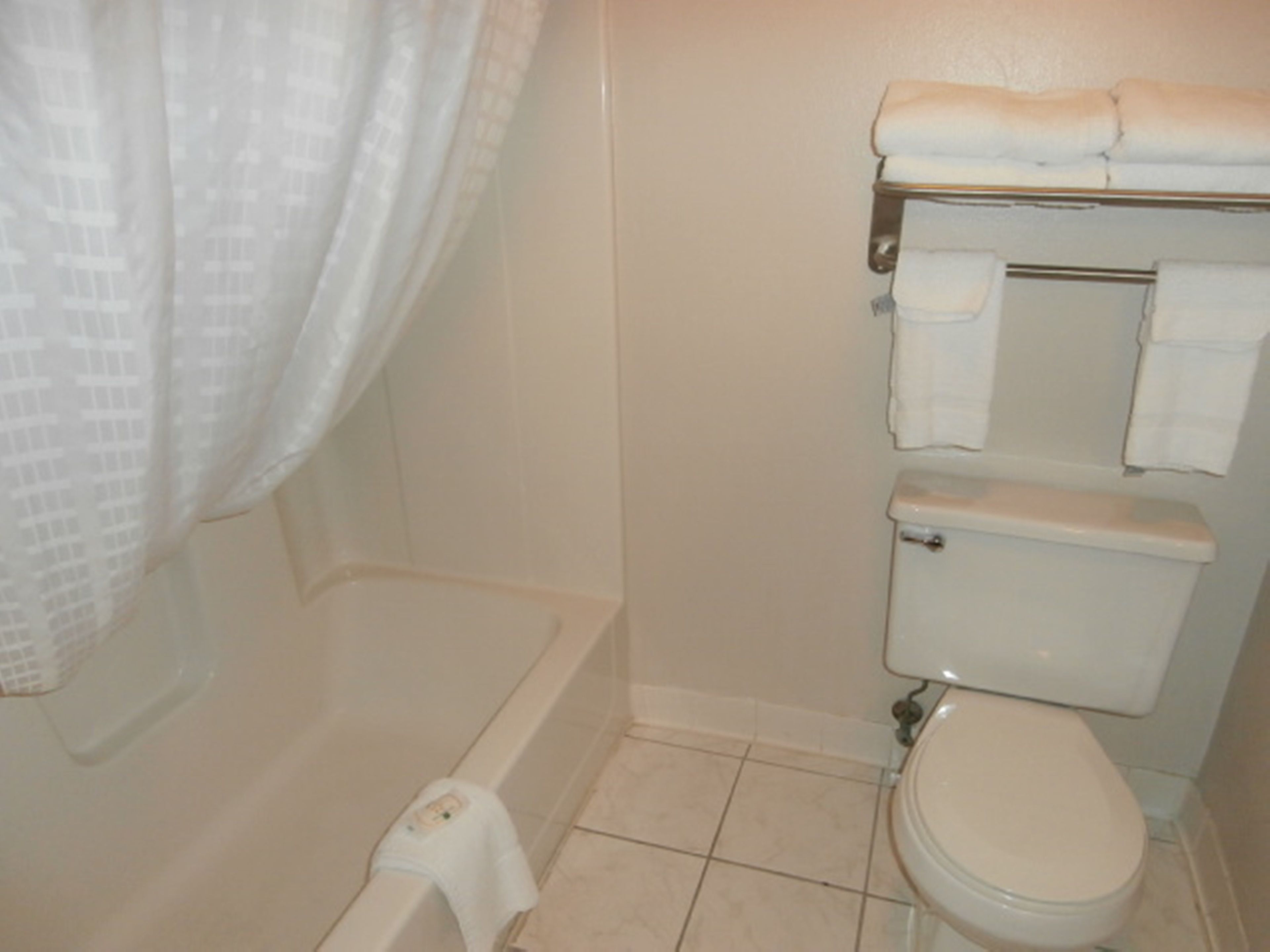 A bathroom with a bathtub, toilet, and a towel rack.