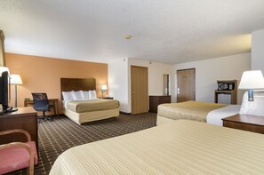 A hotel room with two beds, a desk, a chair, a microwave, and a TV.