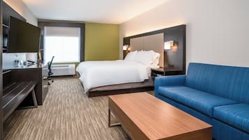 Ein Hotelzimmer mit Bett, Schreibtisch, blauem Sofa, Fernseher und Fenster.