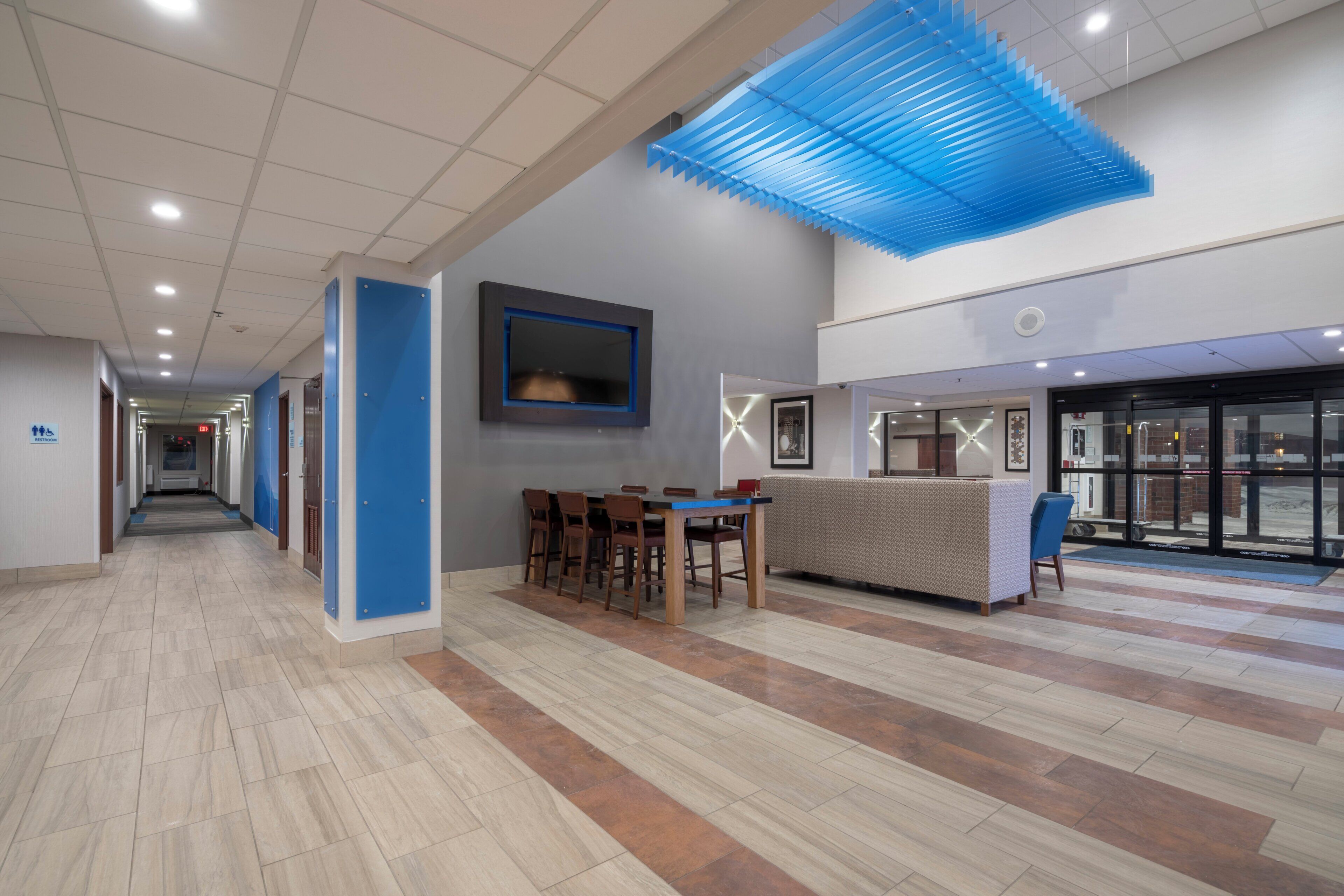 Eine geräumige Lobby mit einer Rezeption, einer Sitzecke und einem freien Weg zum Ausgang.