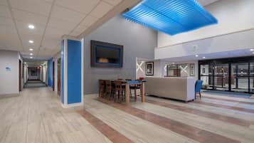 Eine geräumige Lobby mit einer Rezeption, einer Sitzecke und einem freien Weg zum Ausgang.