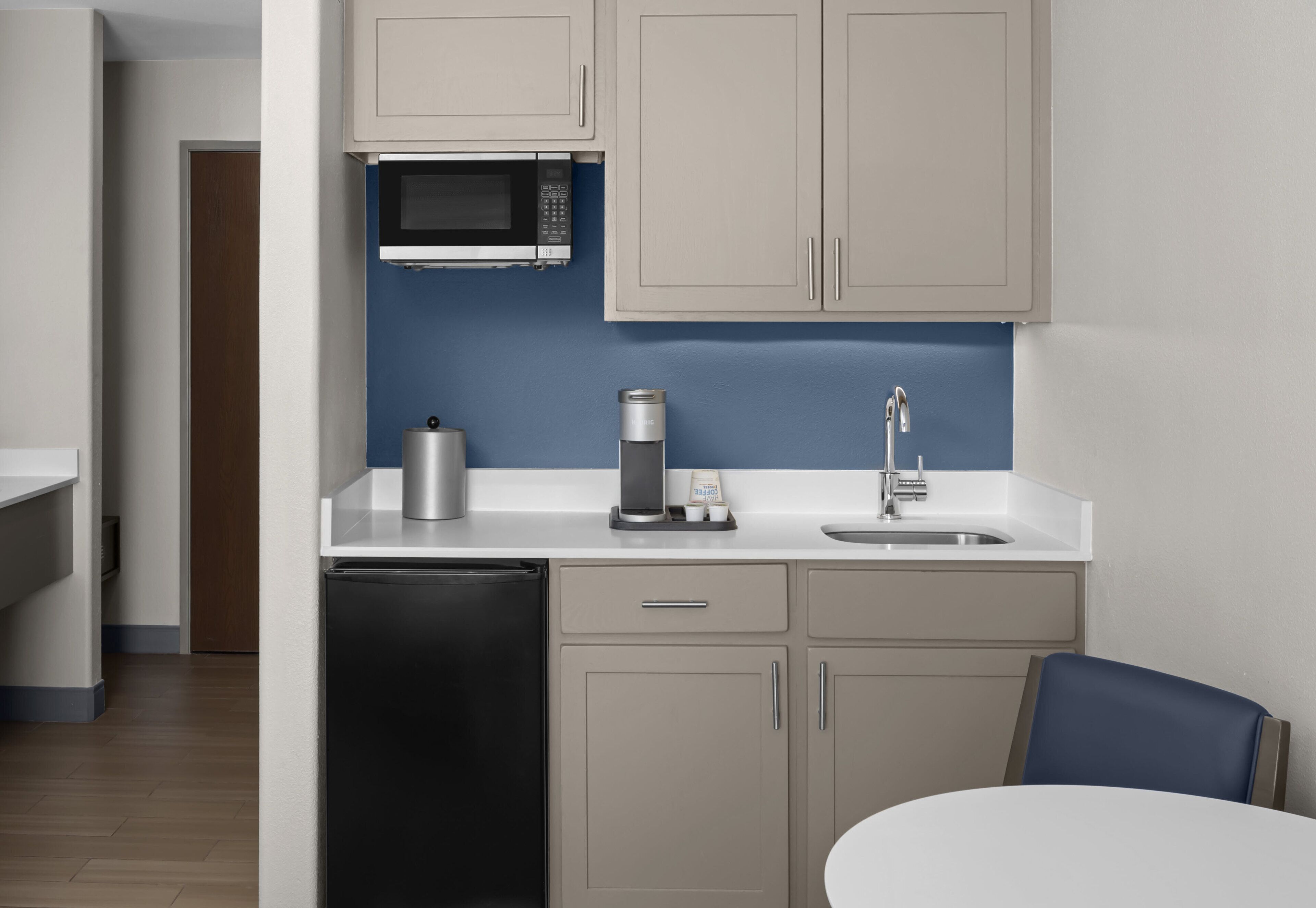 A compact kitchen with a microwave, coffee maker, and sink.