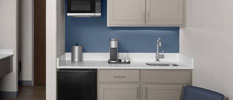A compact kitchen with a microwave, coffee maker, and sink.