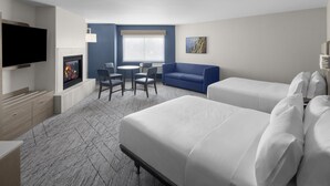 A hotel room with two beds, a TV, a fireplace, a dining area with chairs, and a large window. - Holiday Inn Express & Suites Montrose - Black Canyon Area by IHG (Montrose)