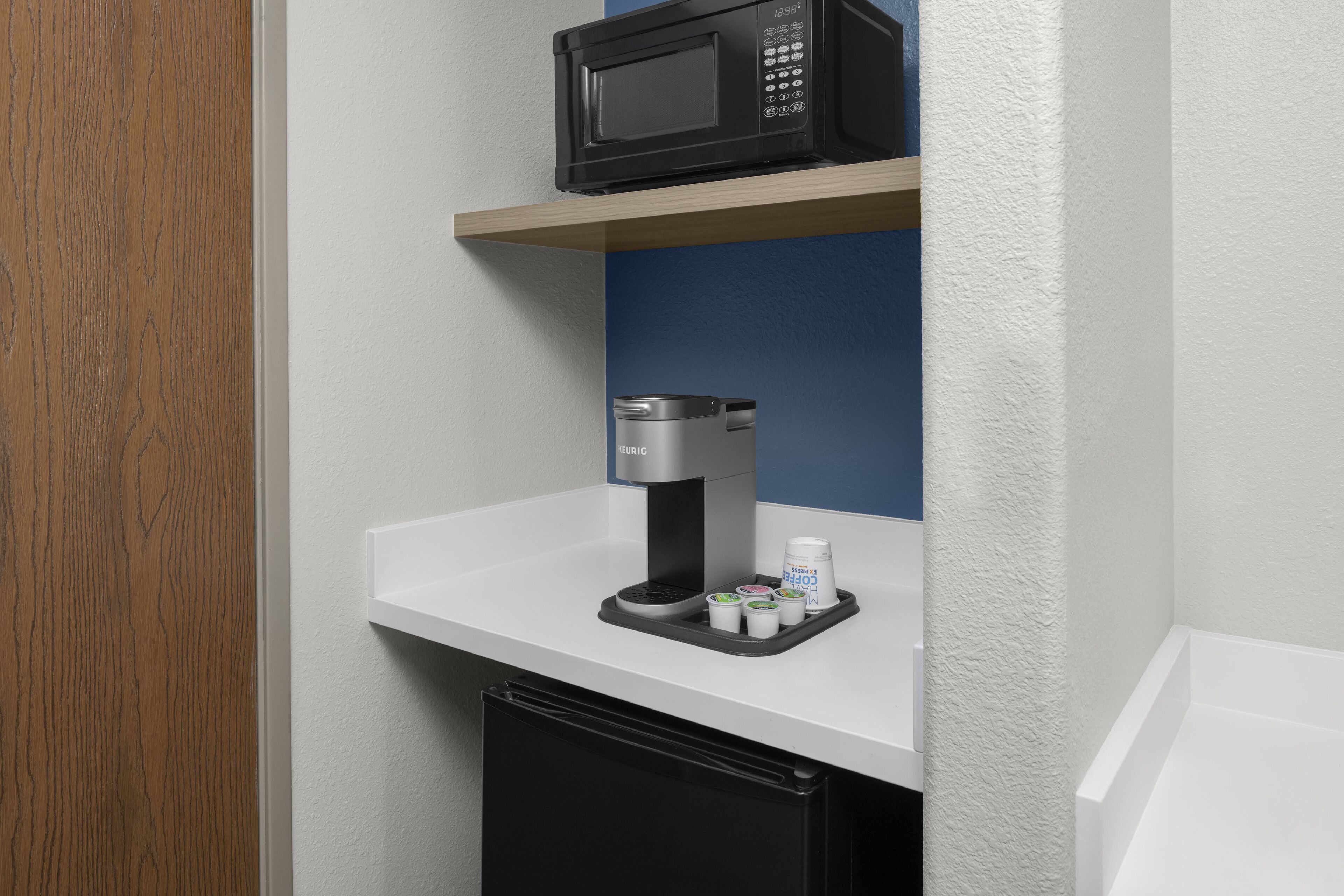 A kitchenette with a microwave, coffee maker, and a small refrigerator.