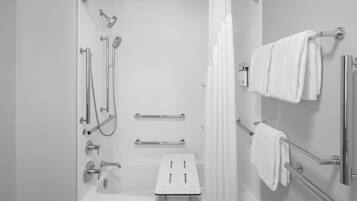 A modern bathroom with a walk-in shower, grab bars, a bench, and towel racks.