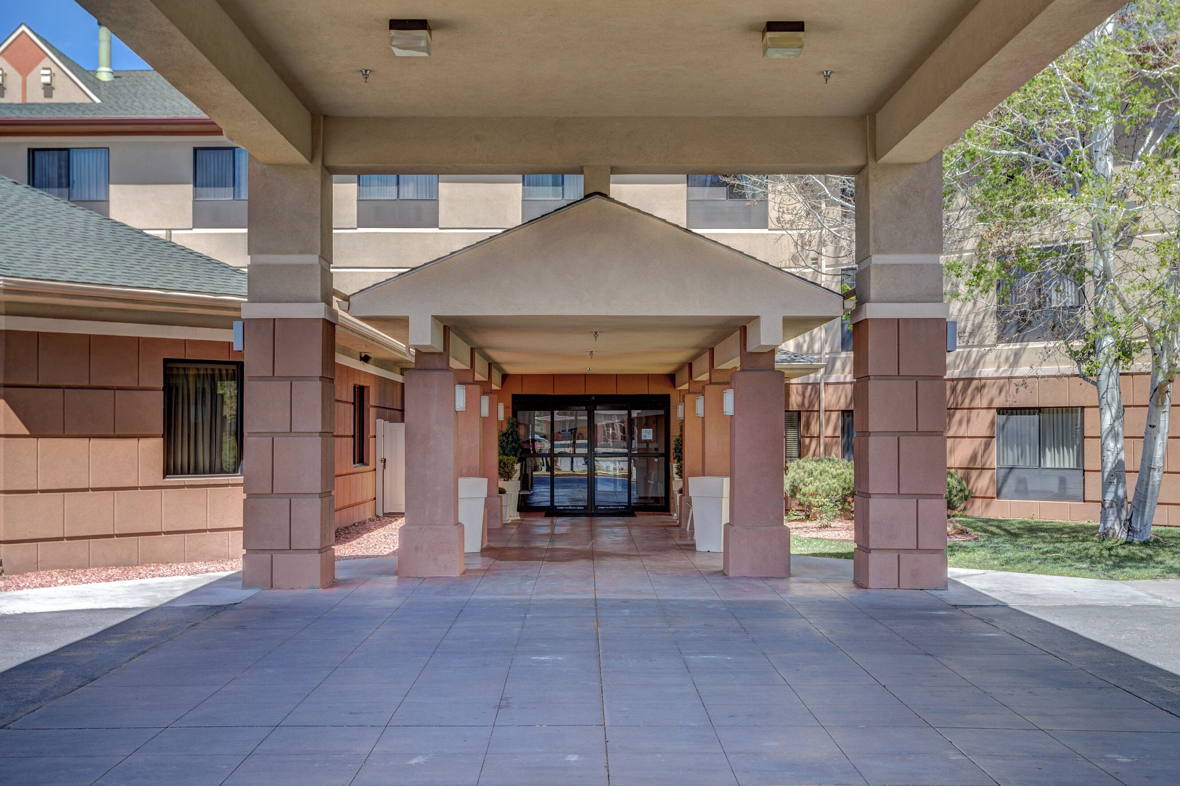A covered entrance with a tiled floor leading to a building entrance.
