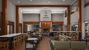 A spacious lobby with a fireplace, seating areas, and a large dining table. - Holiday Inn Express & Suites Montrose - Black Canyon Area by IHG (Montrose)