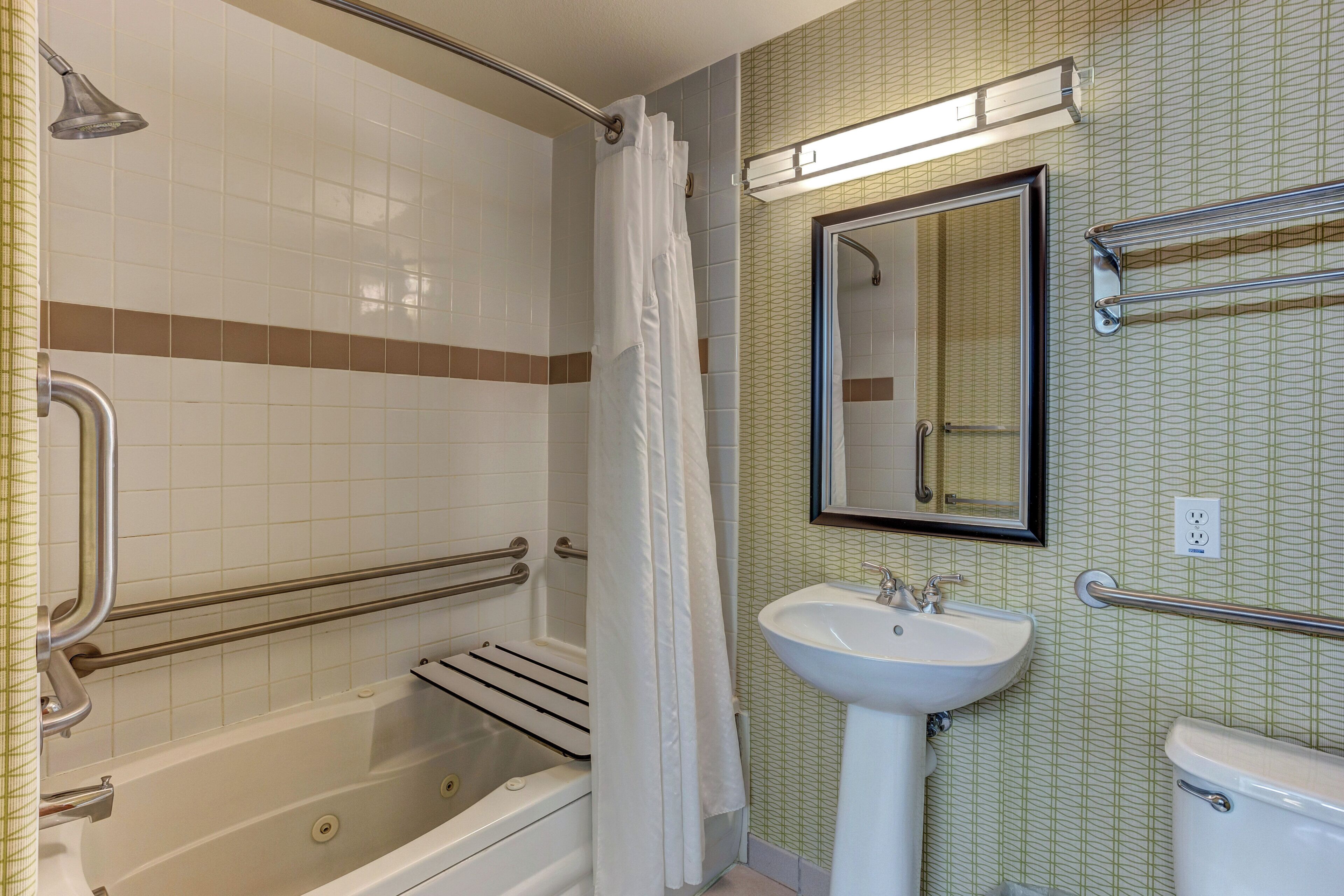 A bathroom with a bathtub, a sink, a mirror, and a shower curtain.