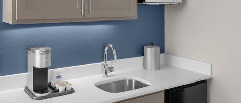 A modern kitchen with a built-in microwave, a coffee maker, and a stainless steel sink.