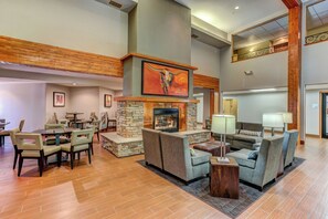 A spacious lobby with a fireplace, seating area, and a dining setup. - Holiday Inn Express & Suites Montrose - Black Canyon Area by IHG (Montrose)
