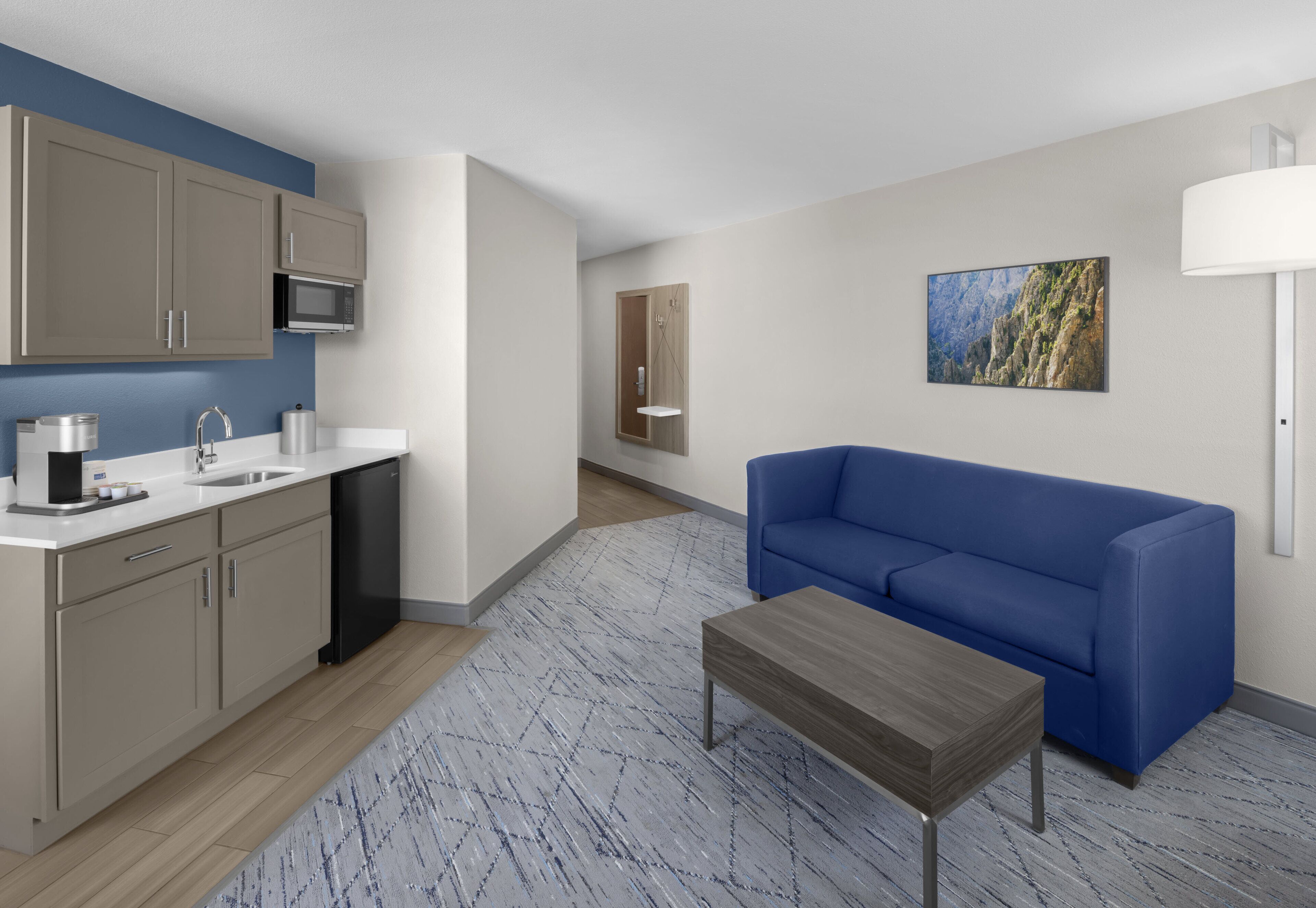 A modern apartment with a kitchen, a blue sofa, and a coffee table.
