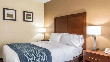 A hotel room with a bed, two bedside lamps, a nightstand with a phone, and two framed pictures on the wall.