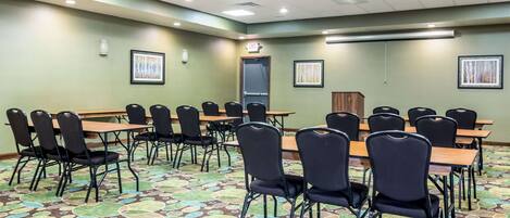 A conference room with a large table and chairs, a patterned carpet, and framed pictures on the walls.