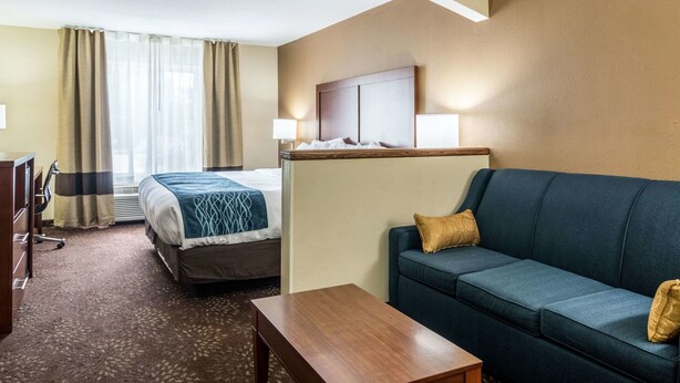 A hotel room with a bed, a sofa, a desk, and a lamp. - Comfort Inn & Suites - Hannibal (Hannibal)