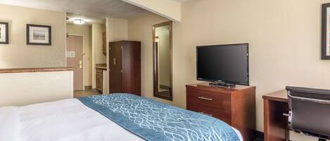 A hotel room with a bed, a desk, a television, and a mirror.