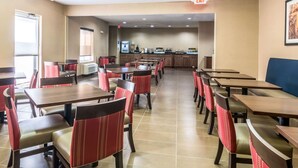 A restaurant with multiple tables and chairs, an exit sign, and a counter area. - Comfort Inn & Suites - Hannibal (Hannibal)