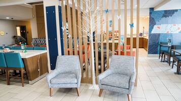 A modern hotel lobby with a reception desk, seating area, and a decorative tree.