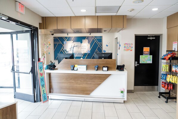 A reception area with a wooden counter, a sign reading "Hollyday Inn Express," and a snack vending machine.