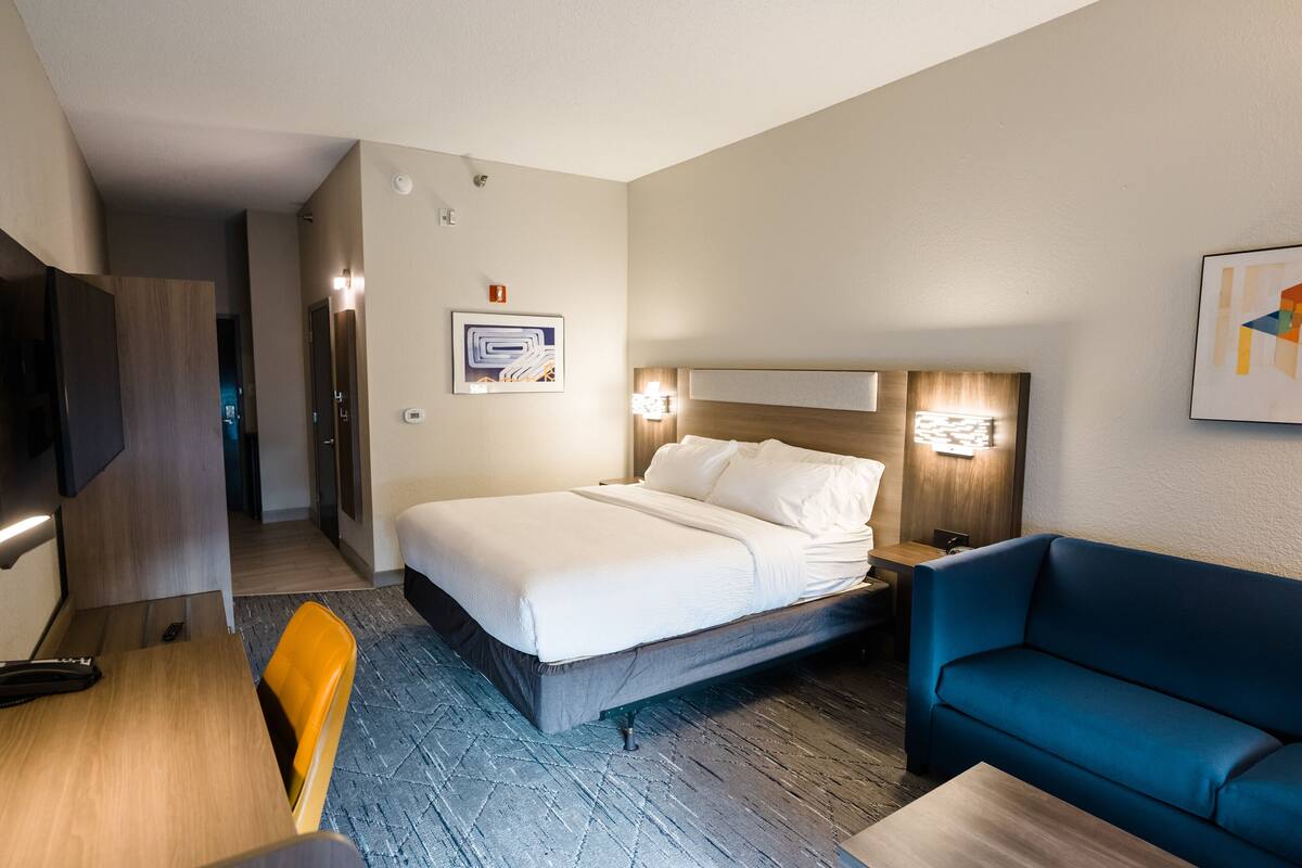 Ein Hotelzimmer mit einem Bett, einem blauen Sofa, einem Holztisch und einem Fernseher.