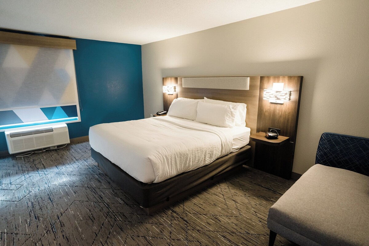 A hotel room with a large bed, bedside tables, a desk, and a chair.