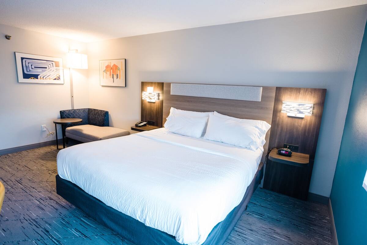 Ein Hotelzimmer mit einem großen Bett, einem Schreibtisch, einem Sessel und zwei Wandlampen.