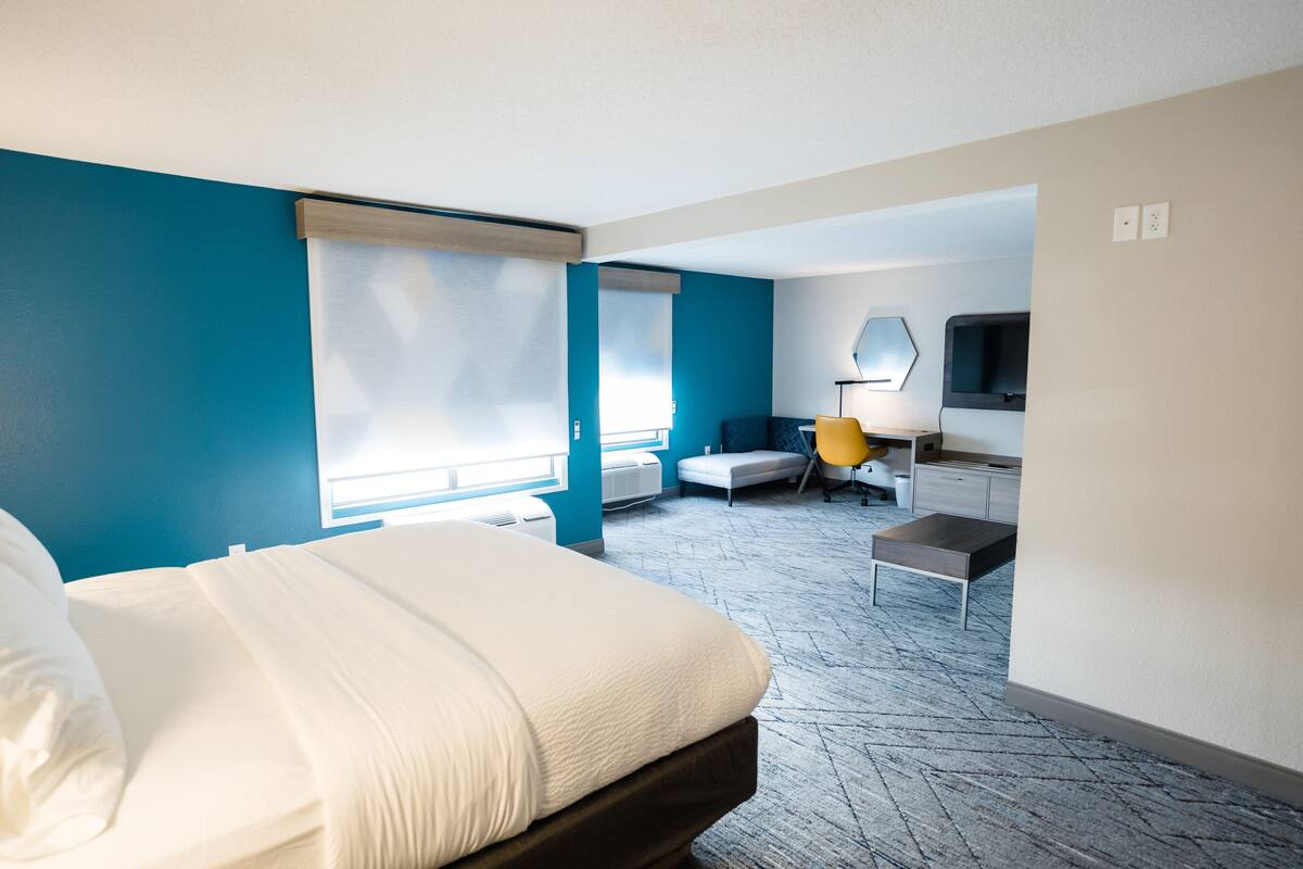 Ein Hotelzimmer mit Bett, Schreibtisch, Stuhl, Fernseher und Fenster.