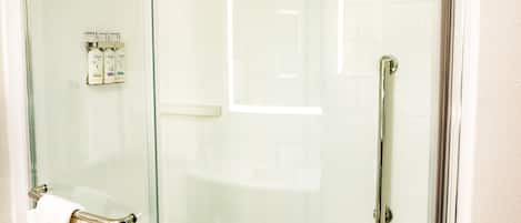 A glass-enclosed shower stall with a white towel hanging on the door handle.