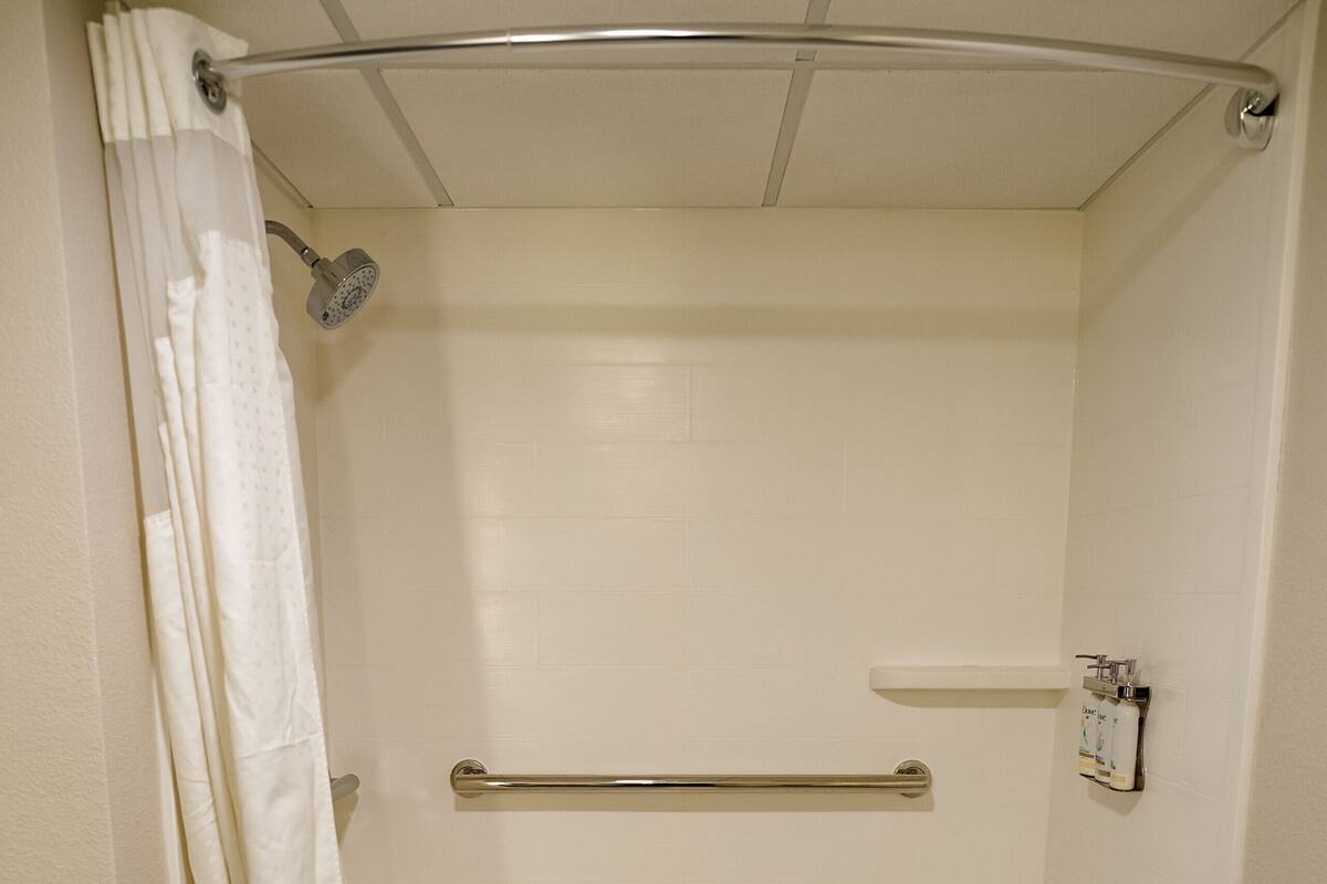 Eine begehbare Dusche mit Haltegriff, Handtuchhalter und Duschbrause.