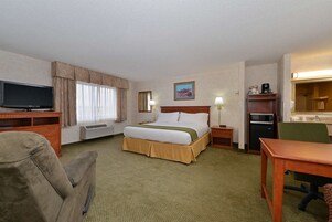 Habitación de hotel con cama, televisión, escritorio, silla, microondas y una mesita.