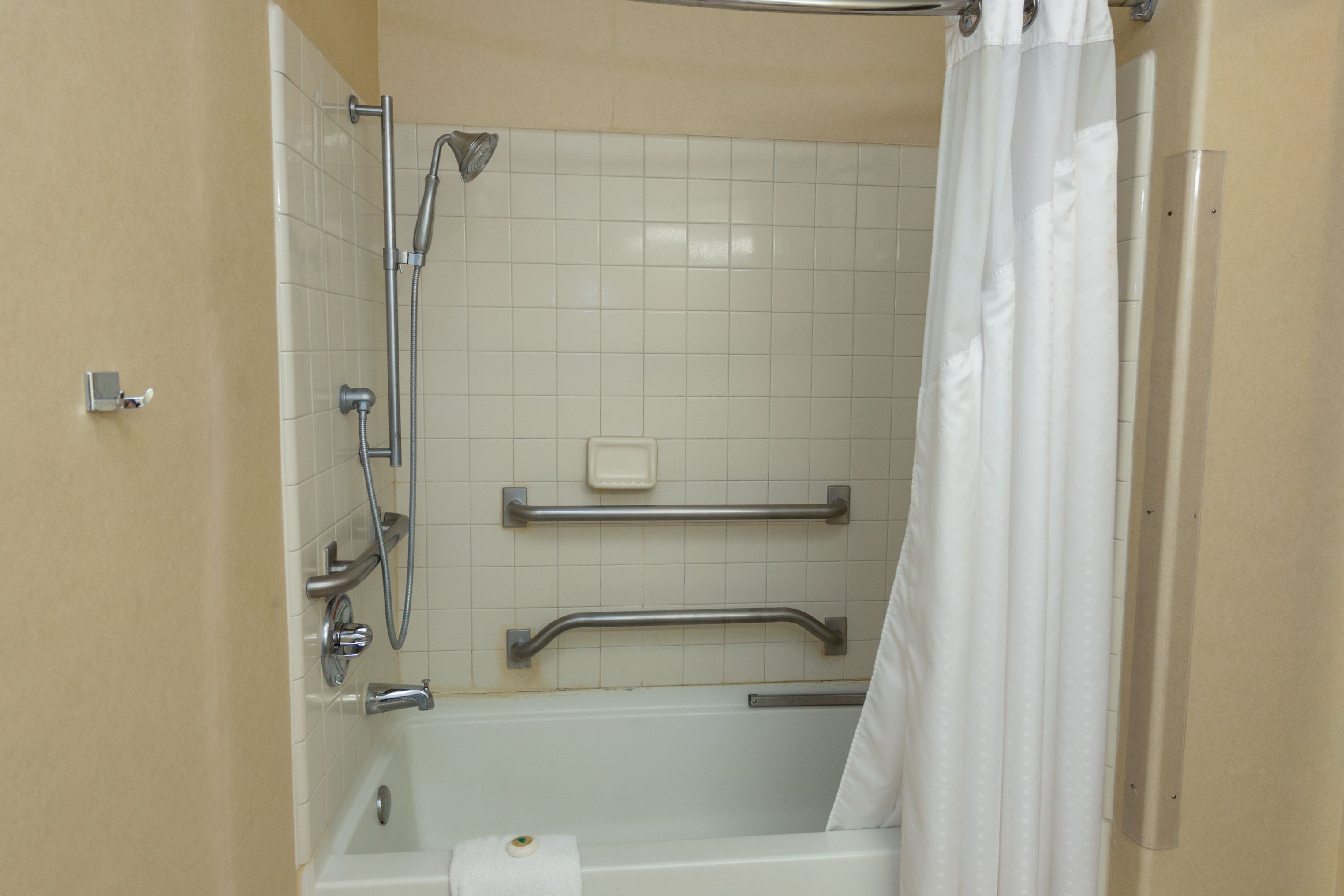 Un baño con bañera, ducha y barra de apoyo.