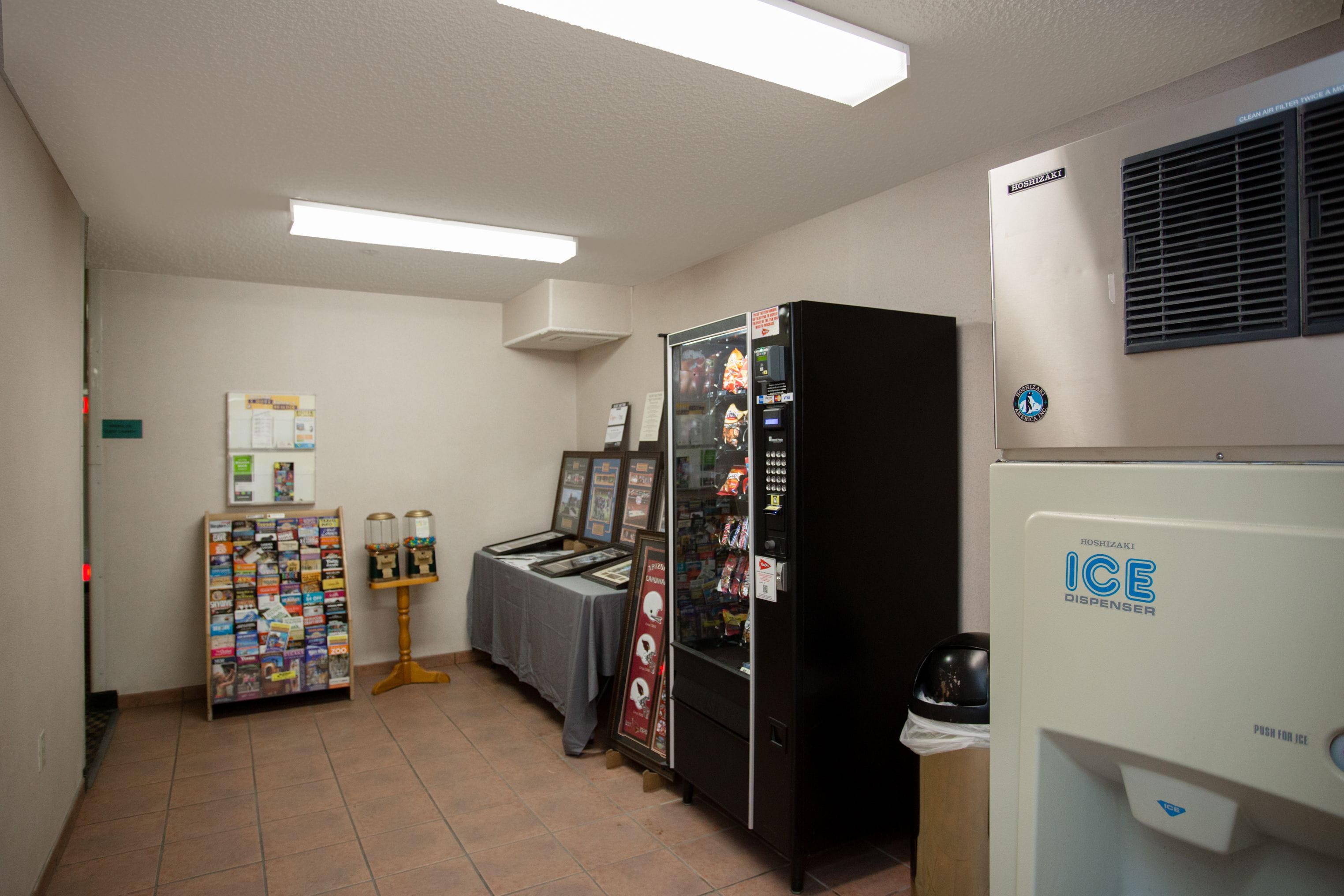 Una habitación con máquina expendedora, refrigerador y una selección de revistas.